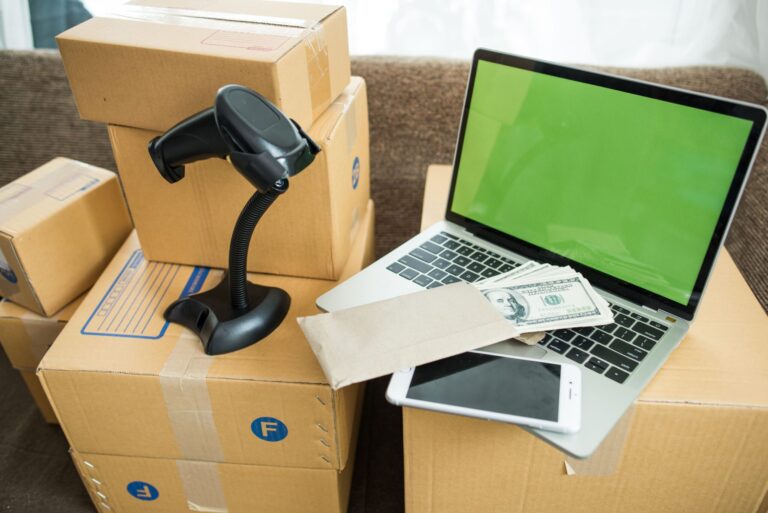 Packs et matériel de déménagement: cartons, scanner/barcode, ordinateur portable avec écran vert, téléphone et billets; tout prêt pour le contexte « matériel déménagement pour professionnel ».