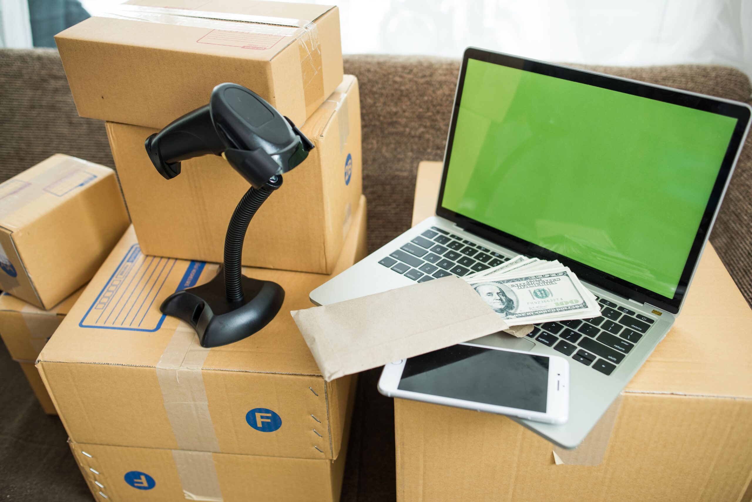 Packs et matériel de déménagement: cartons, scanner/barcode, ordinateur portable avec écran vert, téléphone et billets; tout prêt pour le contexte « matériel déménagement pour professionnel ».