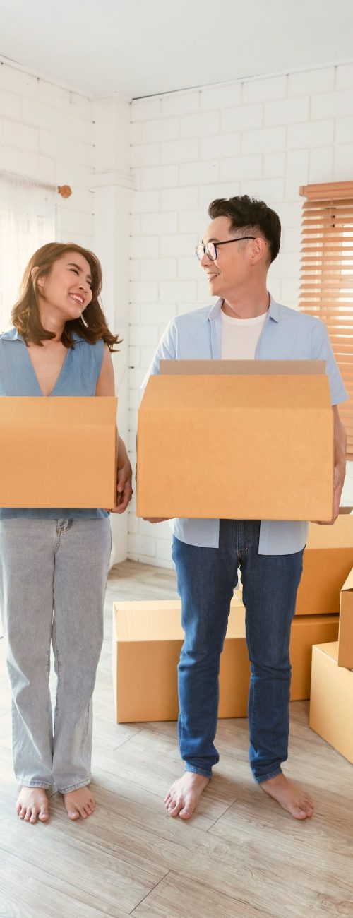 Happy Asian couple holding cardboard box go into new home. Relocation concept